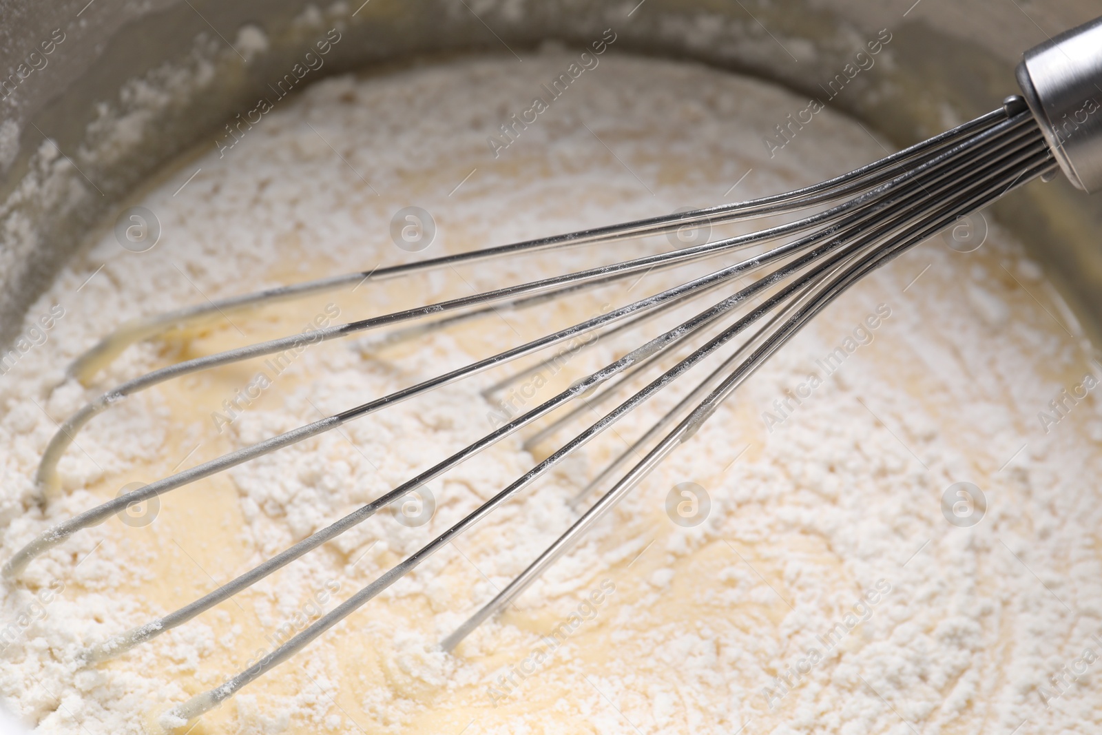 Photo of Whisk and bowl of dough, closeup view