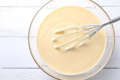 Photo of Whisk and bowl of dough on white wooden table, top view