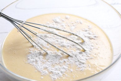 Photo of Whisk and glass bowl of dough, closeup