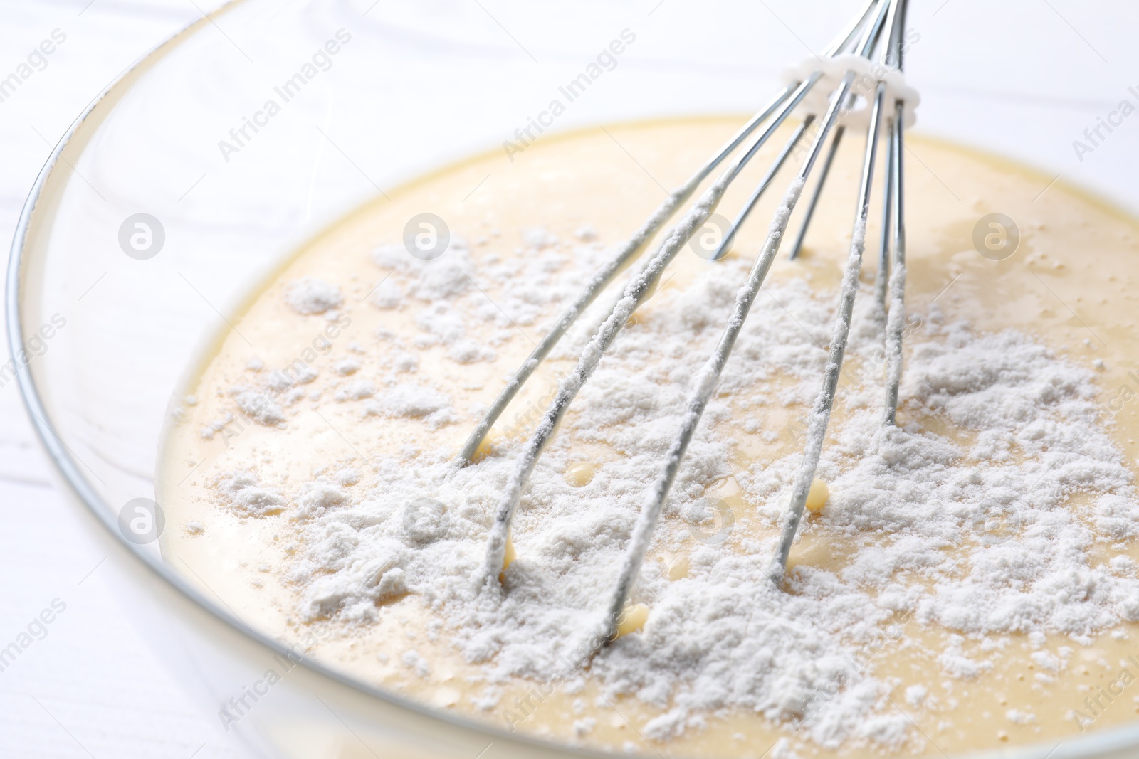 Photo of Whisk and glass bowl of dough, closeup