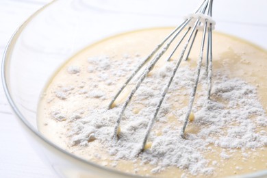 Photo of Whisk and glass bowl of dough, closeup