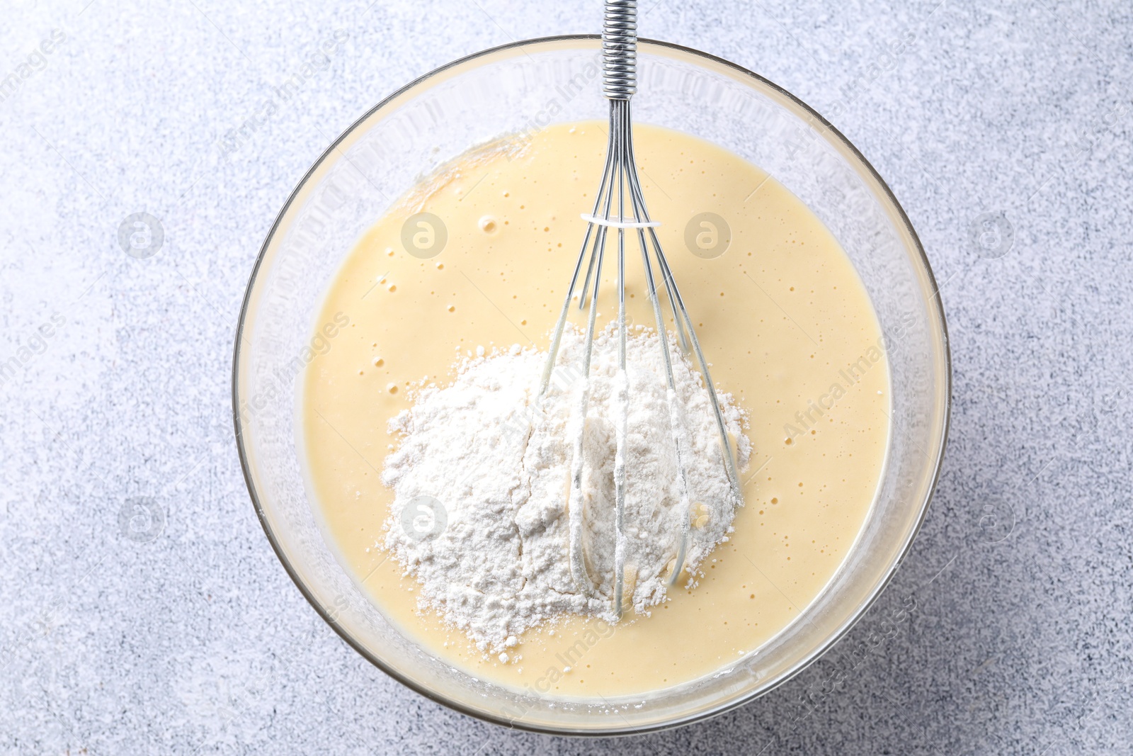 Photo of Whisk and bowl of dough on grey table, top view