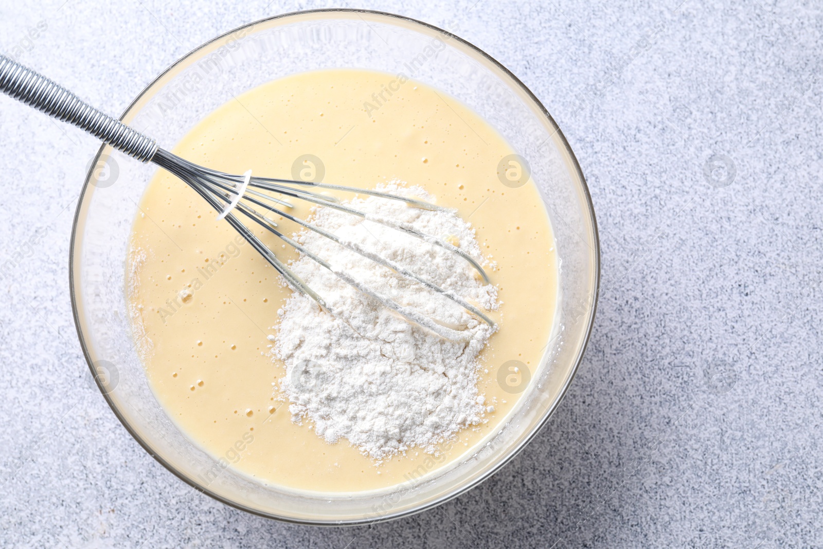 Photo of Whisk and bowl of dough on grey table, top view. Space for text