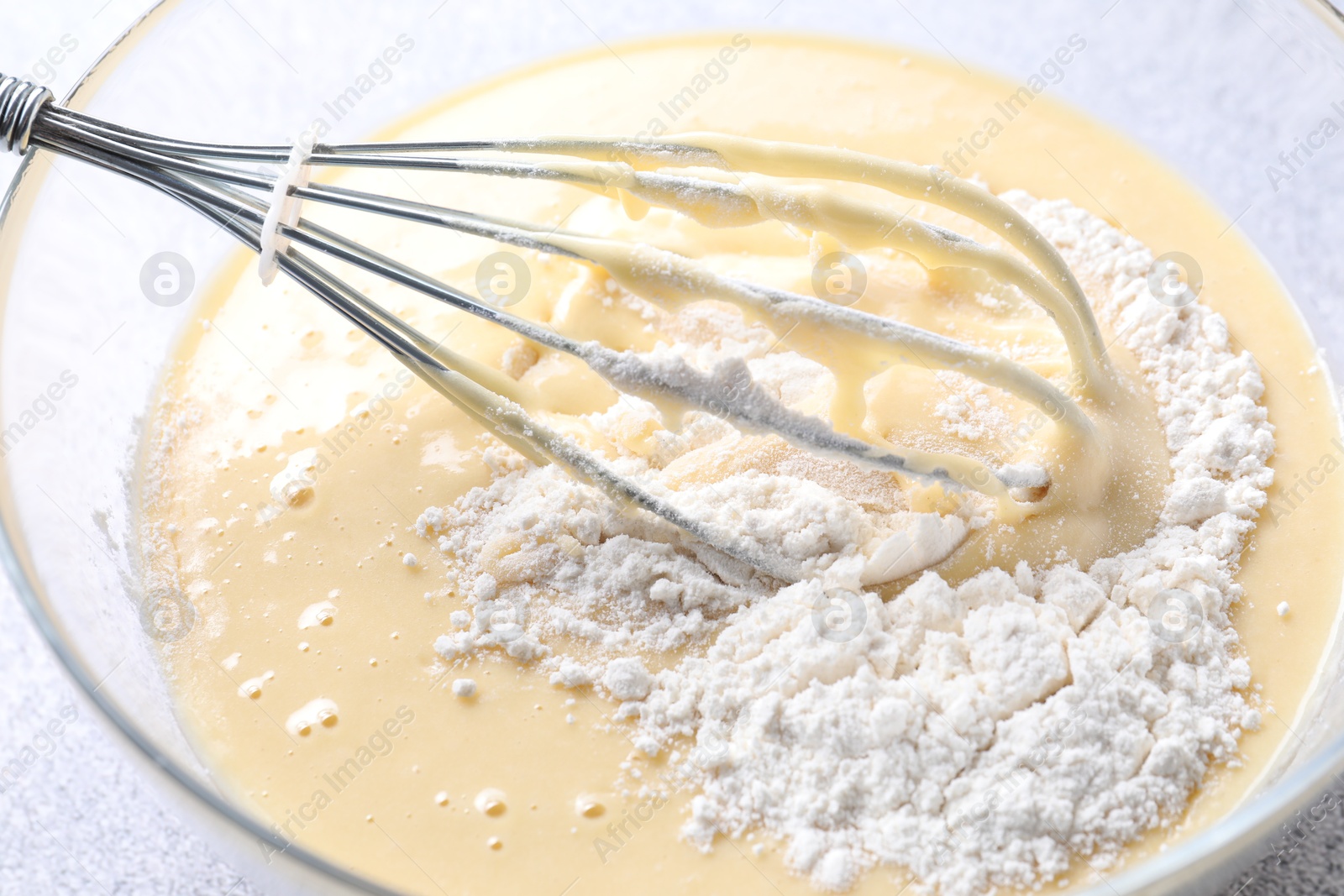 Photo of Whisk and bowl of dough on table, closeup