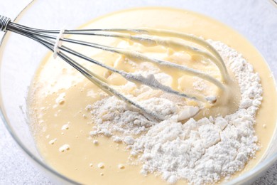 Photo of Whisk and bowl of dough on table, closeup