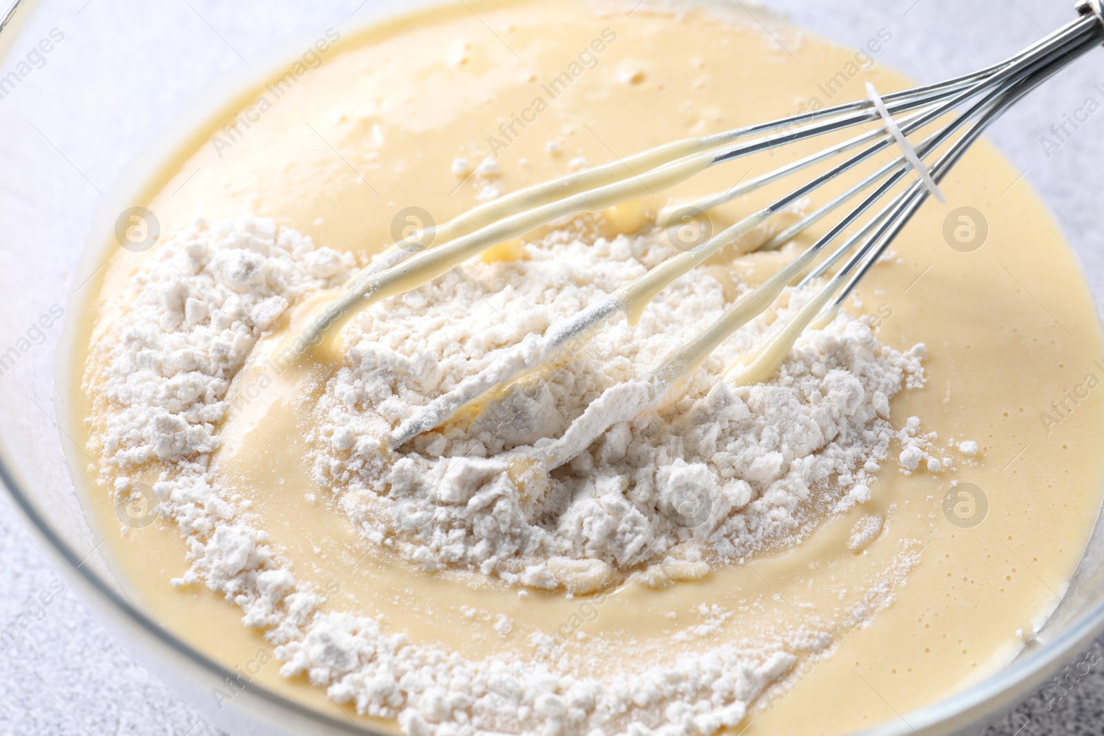 Photo of Whisk and bowl of dough on table, closeup