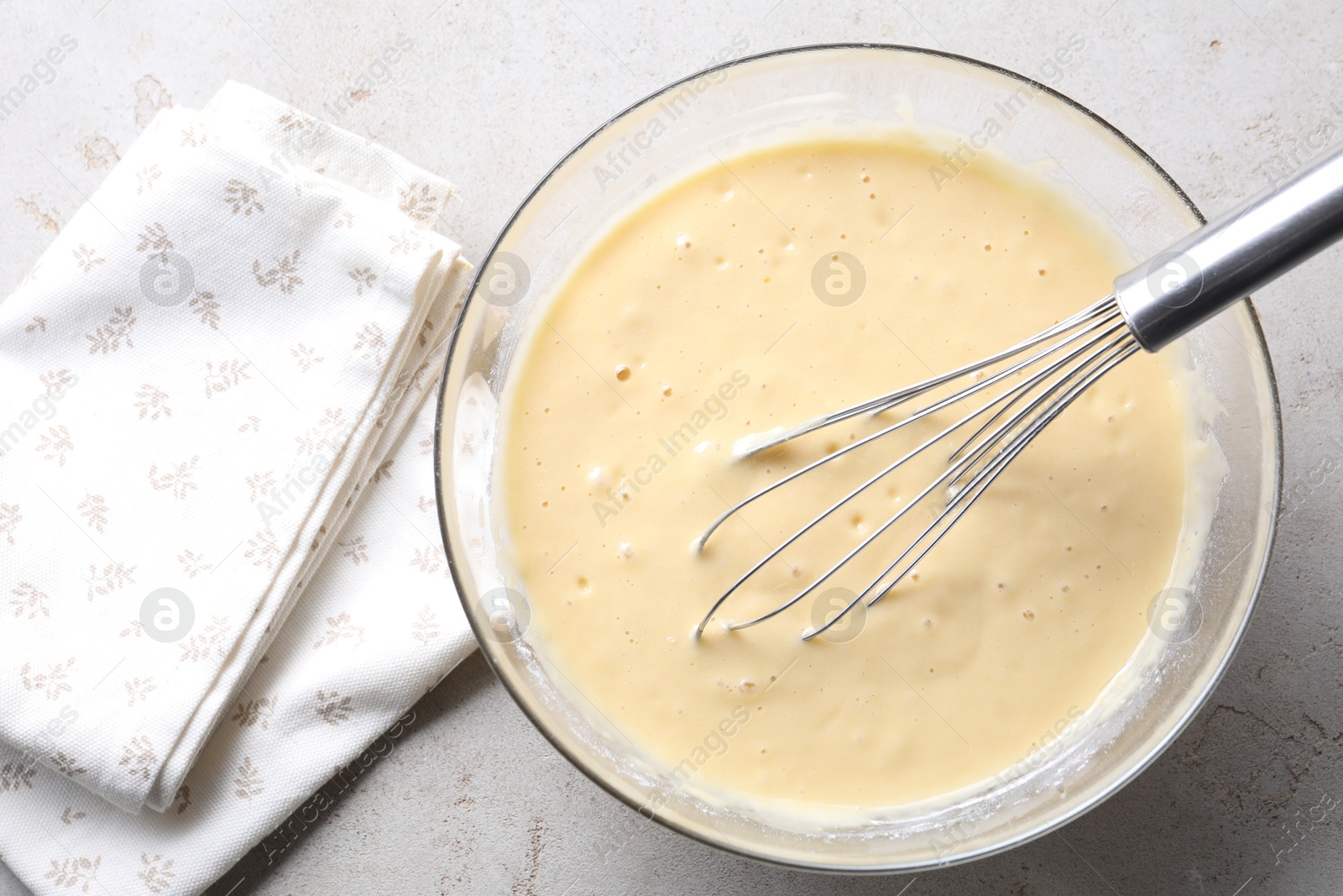 Photo of Whisk and bowl of dough on grey table, top view