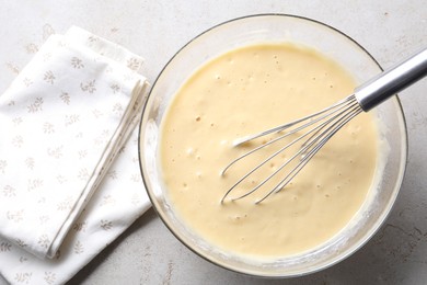 Photo of Whisk and bowl of dough on grey table, top view