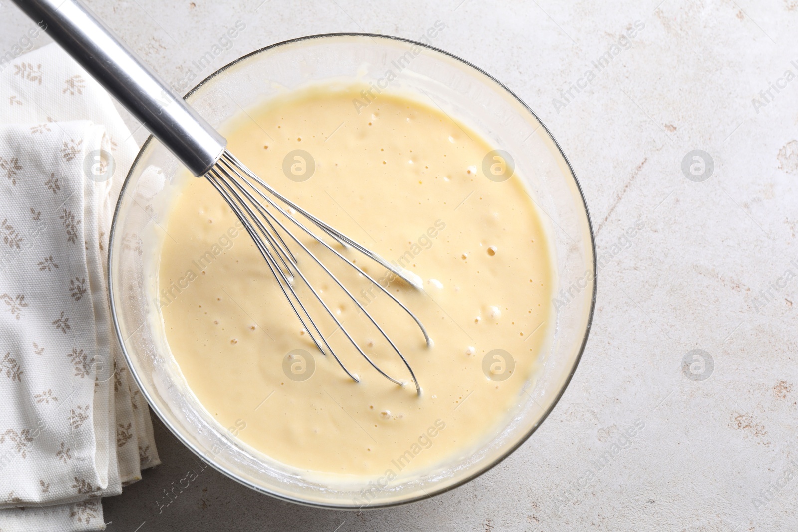 Photo of Whisk and bowl of dough on grey table, top view