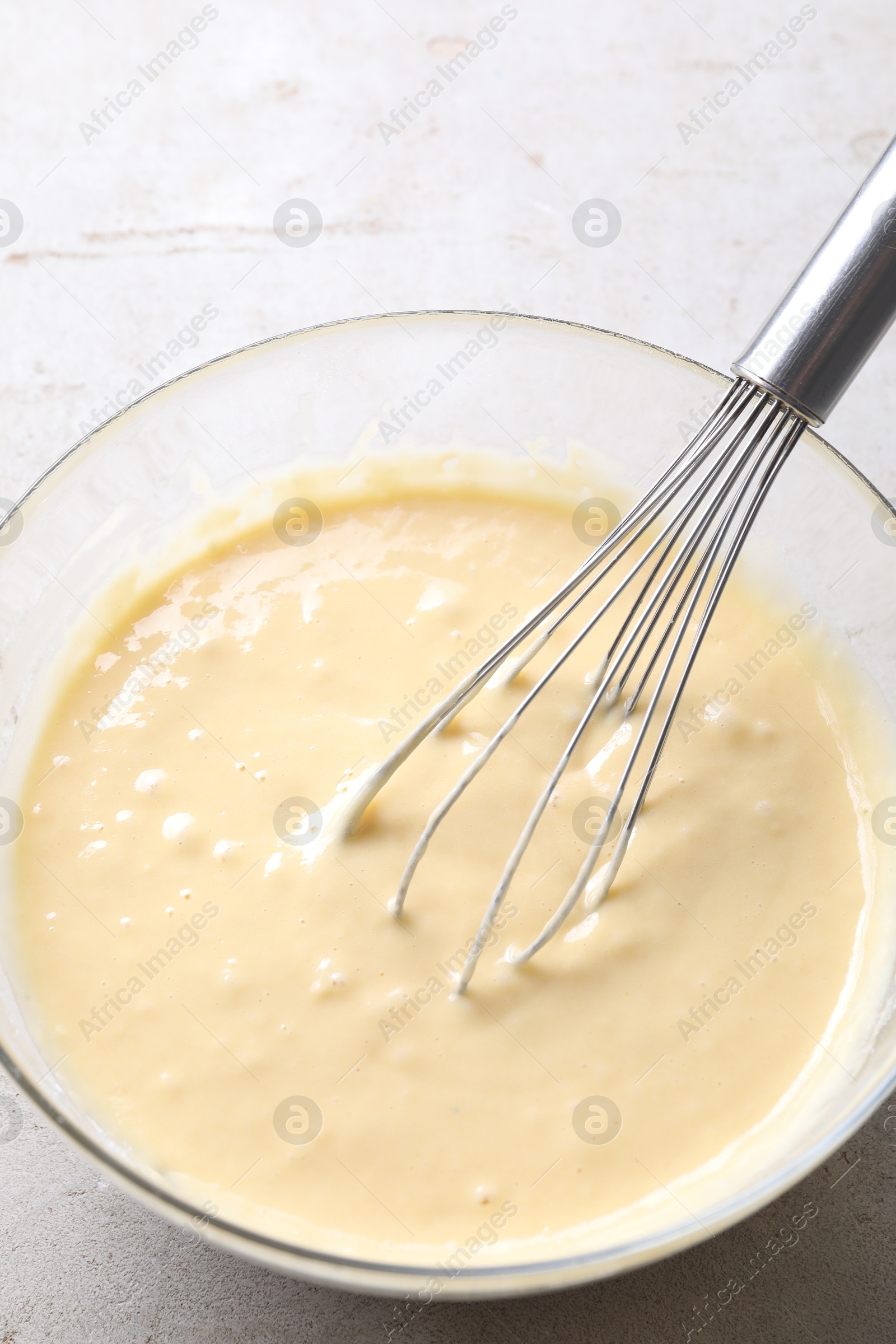 Photo of Whisk and bowl of dough on grey table, above view