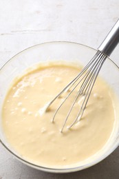 Photo of Whisk and bowl of dough on grey table, above view