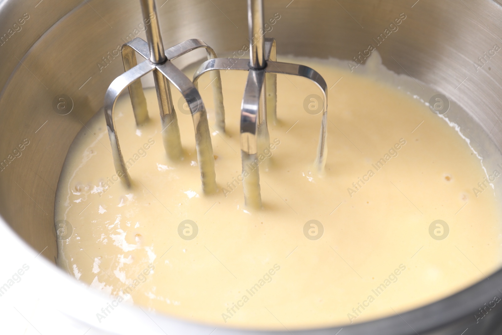 Photo of Making dough in bowl with hand mixer, closeup