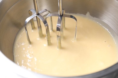 Photo of Making dough in bowl with hand mixer, closeup