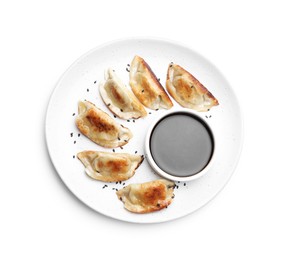 Photo of Delicious fried gyoza dumplings with sesame seeds and soy sauce isolated on white, top view