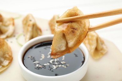 Eating fried gyoza dumplings at white table, closeup