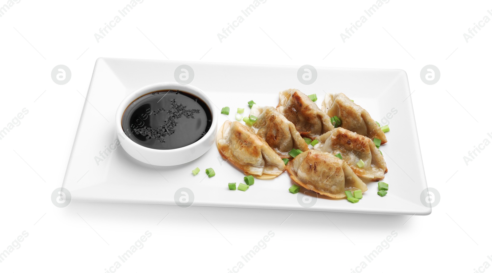 Photo of Delicious fried gyoza dumplings with green onions and soy sauce isolated on white