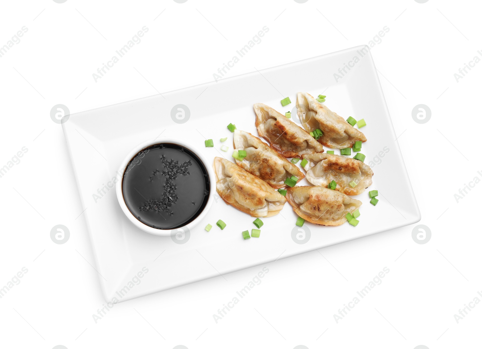 Photo of Delicious fried gyoza dumplings with green onions and soy sauce isolated on white, top view