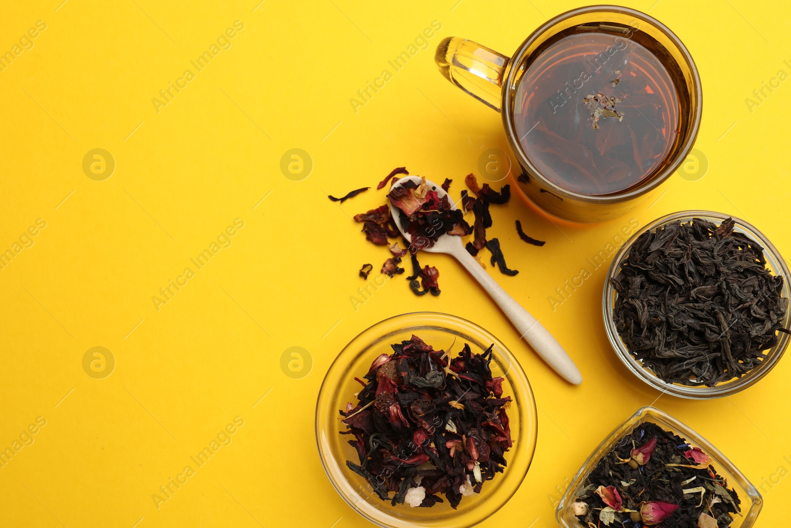 Photo of Aromatic tea and dried leaves on yellow background, flat lay. Space for text