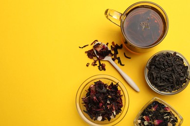 Photo of Aromatic tea and dried leaves on yellow background, flat lay. Space for text