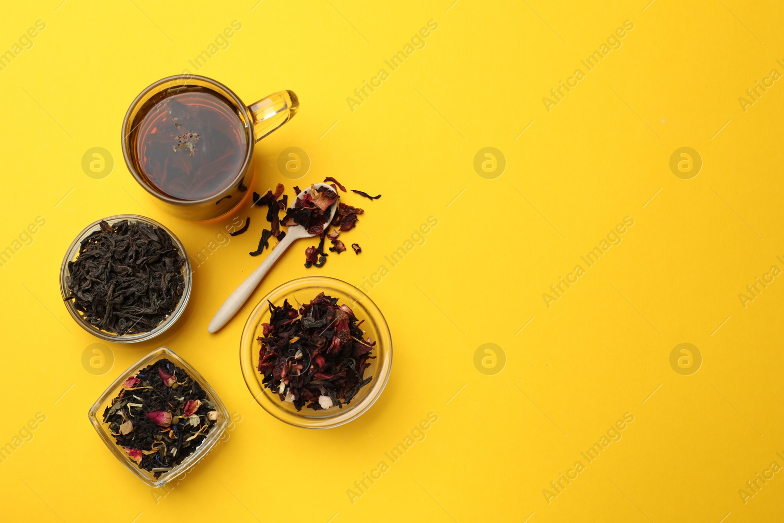 Photo of Aromatic tea and dried leaves on yellow background, flat lay. Space for text