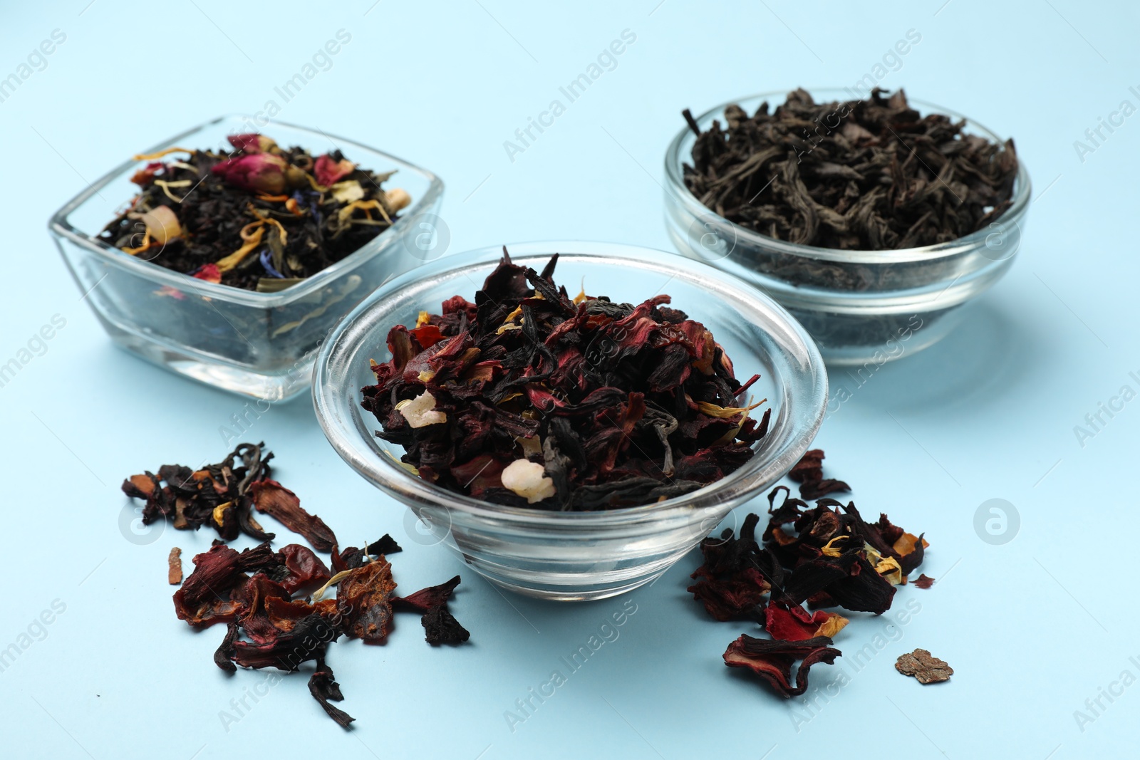 Photo of Different types of tea brew on light blue background, closeup