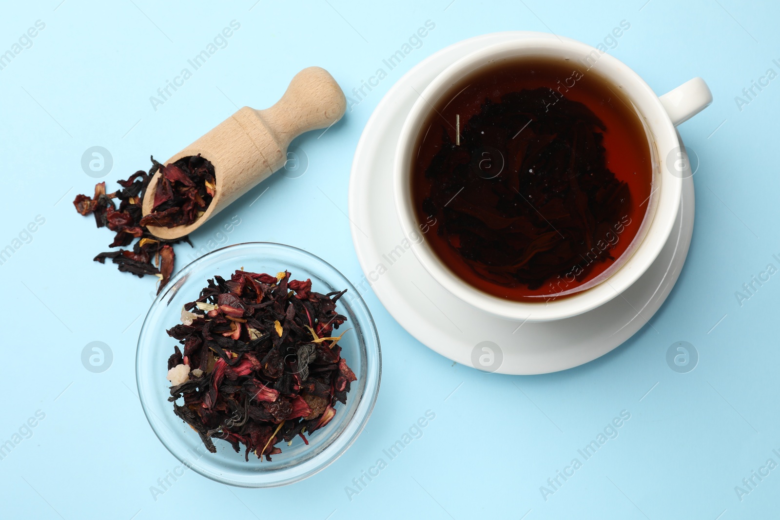 Photo of Aromatic tea and dried leaves on light blue background, flat lay