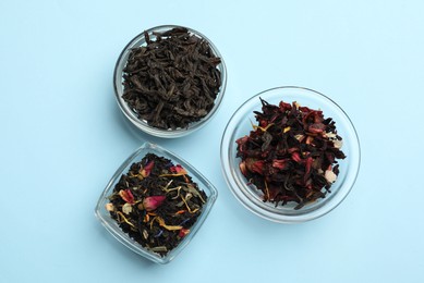 Photo of Different types of tea brew on light blue background, flat lay