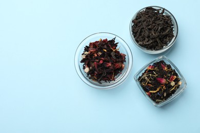 Photo of Different types of tea brew on light blue background, flat lay. Space for text