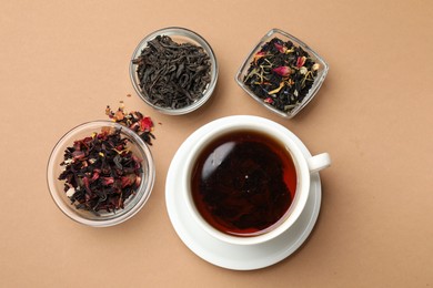 Photo of Aromatic tea and dried leaves on brown background, flat lay