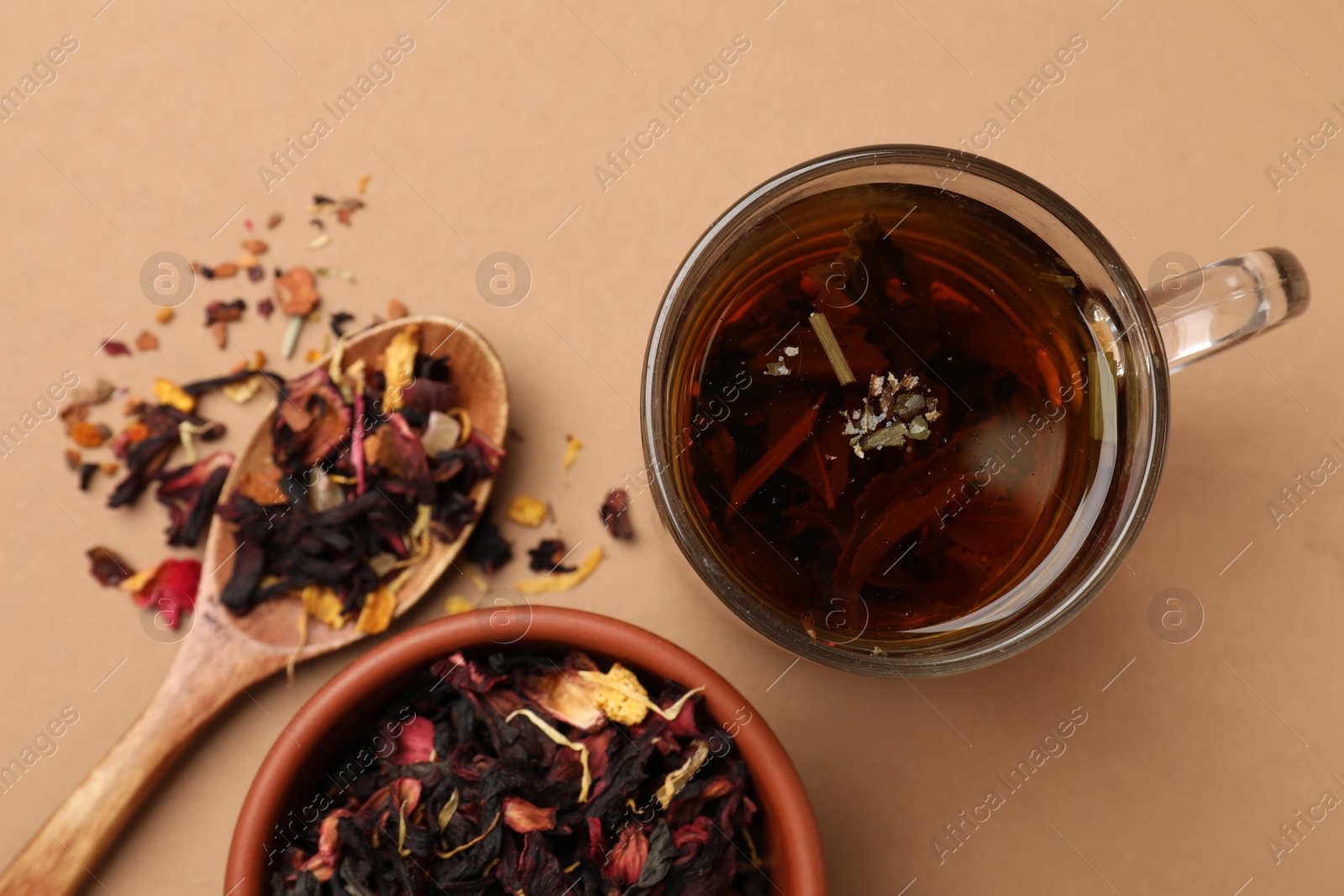 Photo of Aromatic tea and dried leaves on brown background, flat lay