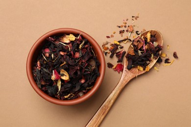 Photo of Dried tea leaves in bowl and spoon on brown background, top view