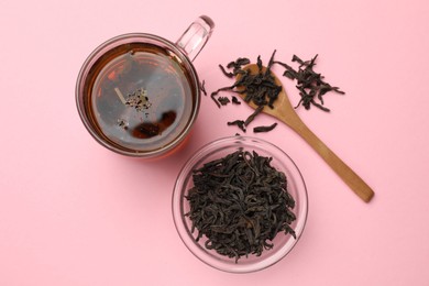 Photo of Aromatic tea and dried leaves on light pink background, flat lay