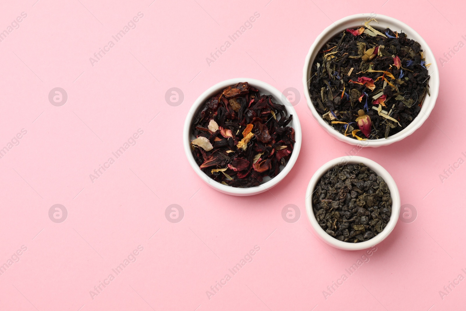 Photo of Different types of tea brew on light pink background, flat lay. Space for text