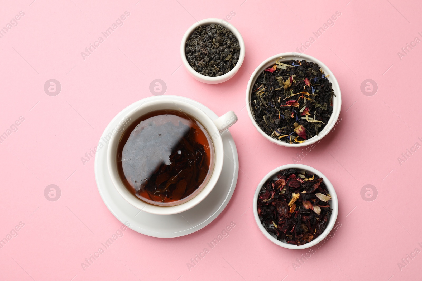 Photo of Aromatic tea and dried leaves on light pink background, flat lay