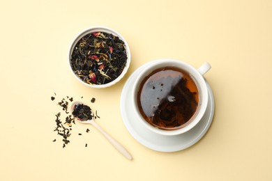 Photo of Aromatic tea and dried leaves on beige background, flat lay