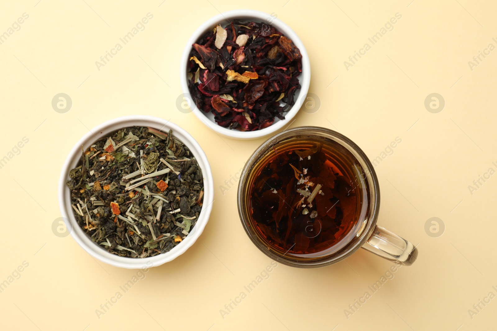 Photo of Aromatic tea and dried leaves on beige background, flat lay