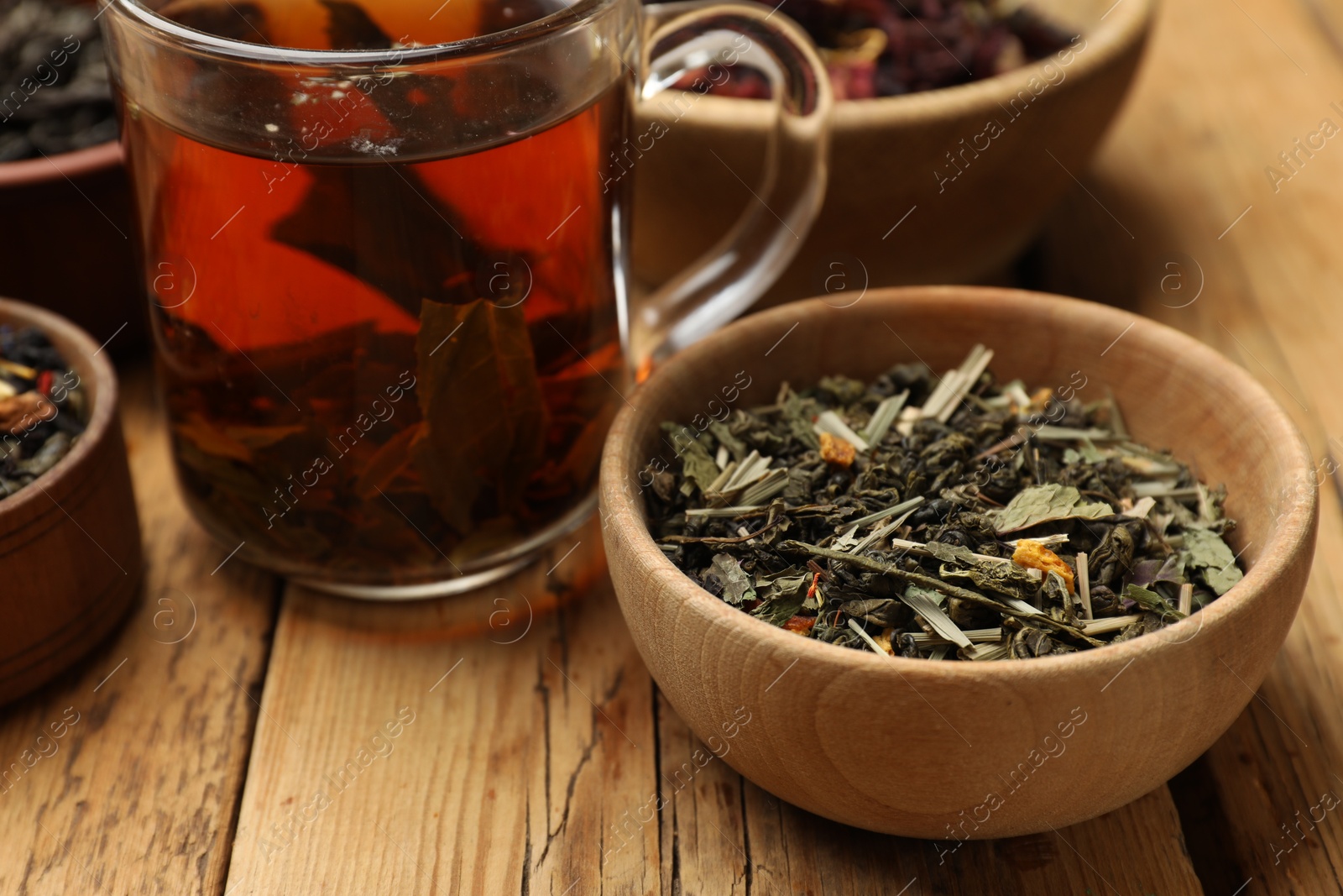 Photo of Aromatic tea and dried leaves on wooden table, closeup