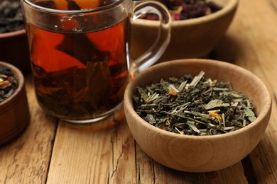 Photo of Aromatic tea and dried leaves on wooden table, closeup