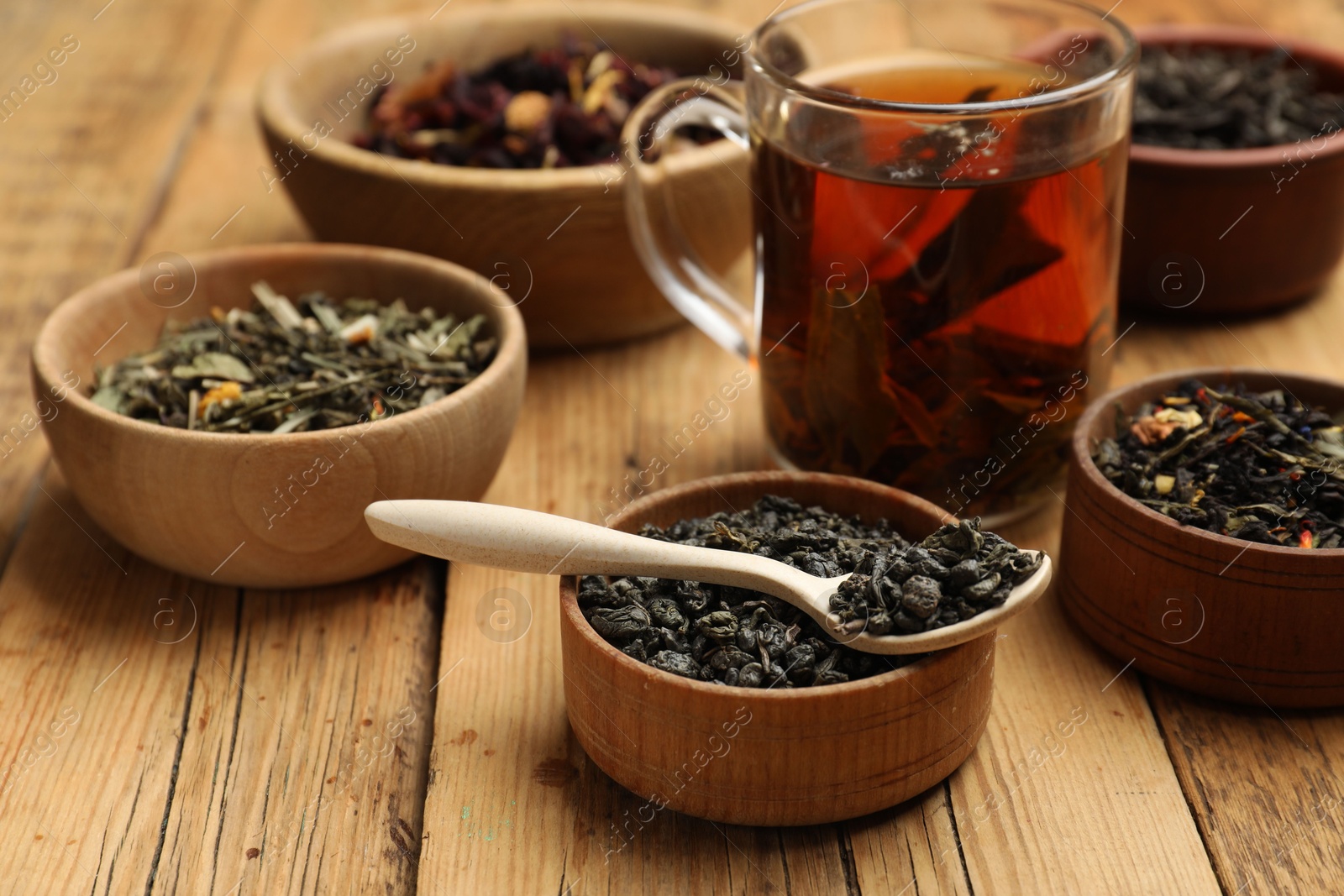 Photo of Aromatic tea and dried leaves on wooden table, closeup