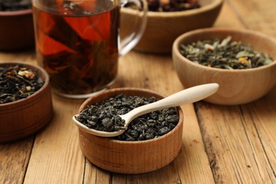 Photo of Aromatic tea and dried leaves on wooden table, closeup