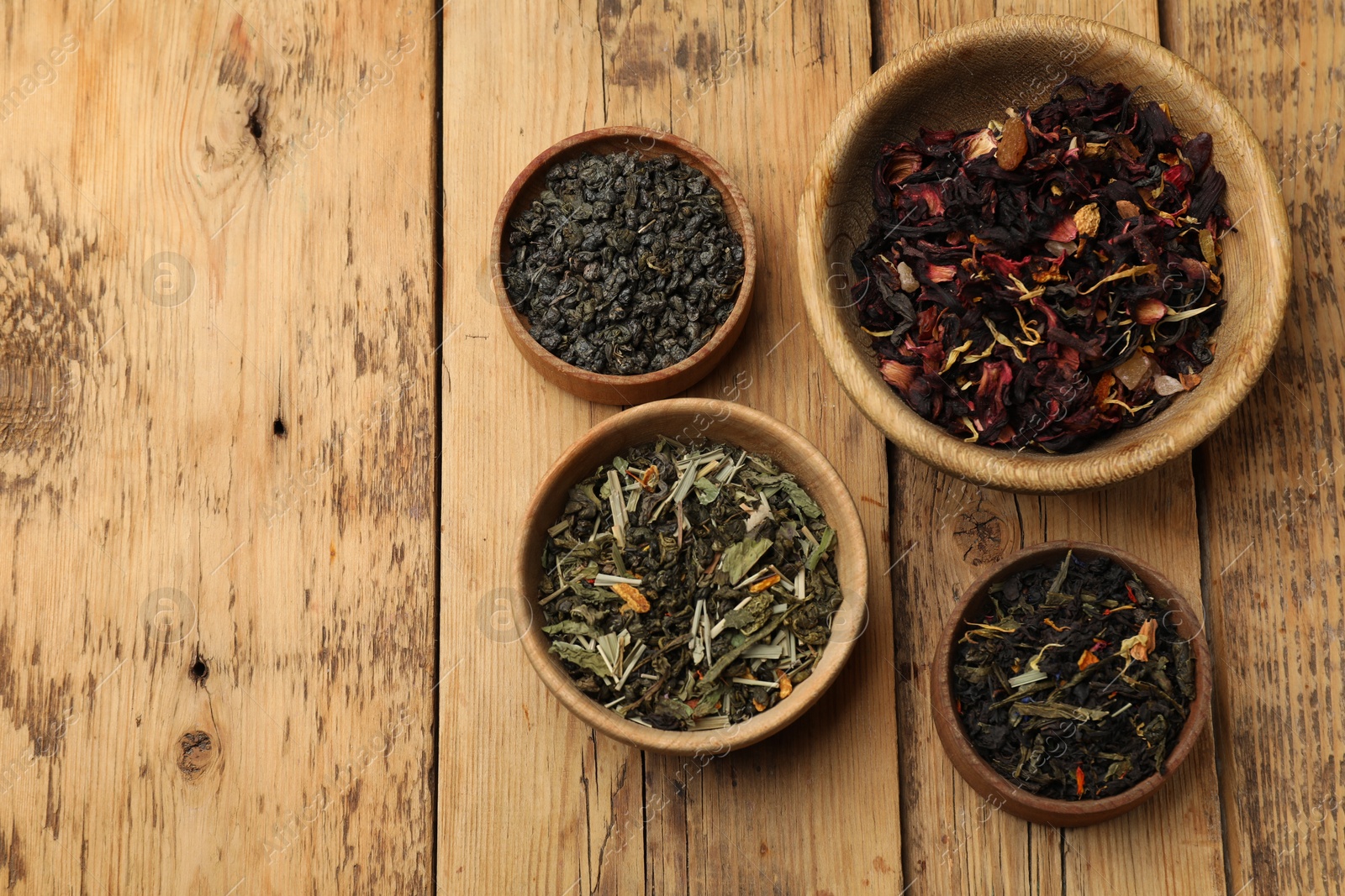 Photo of Different types of tea brew on wooden table, flat lay. Space for text