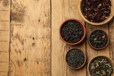 Photo of Different types of tea brew on wooden table, flat lay. Space for text