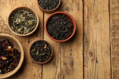 Photo of Different types of tea brew on wooden table, flat lay. Space for text