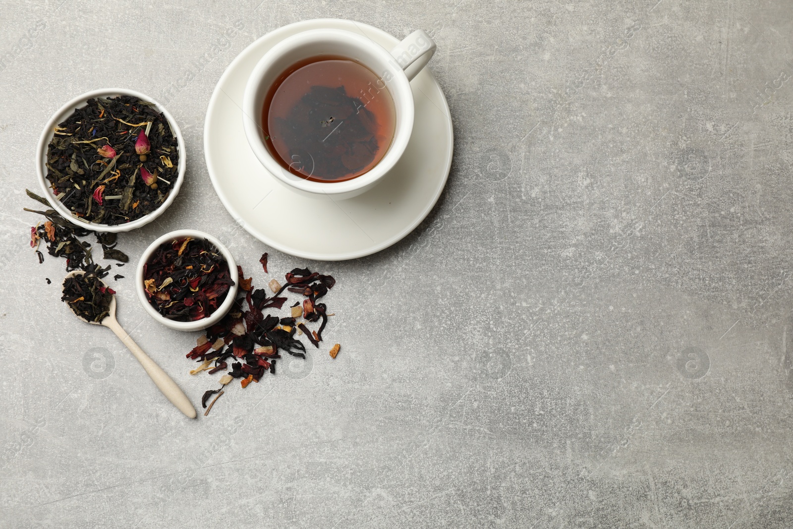 Photo of Aromatic tea and dried leaves on grey table, flat lay. Space for text