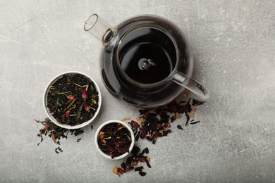 Photo of Aromatic tea and dried leaves on grey table, flat lay