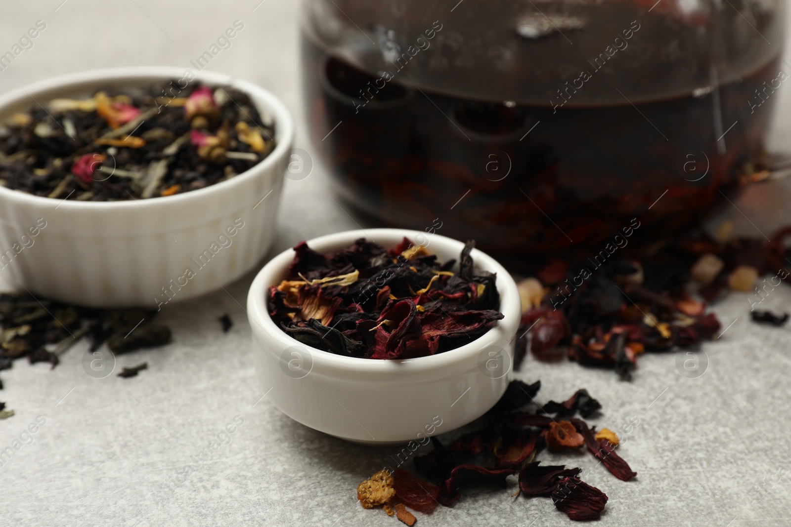 Photo of Aromatic tea and dried leaves on grey table, closeup