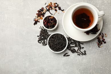 Photo of Aromatic tea and dried leaves on grey table, flat lay. Space for text