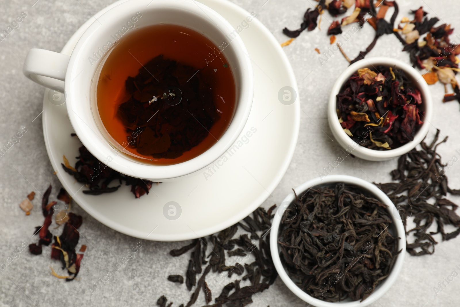 Photo of Aromatic tea and dried leaves on grey table, flat lay