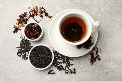 Photo of Aromatic tea and dried leaves on grey table, flat lay