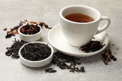 Photo of Aromatic tea and dried leaves on grey table, closeup